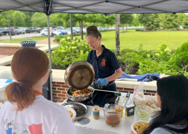 Dr. Annie Kirby cooking food outside for students.
