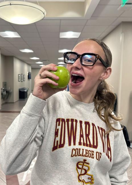 VCOM student smiling while eating an apple