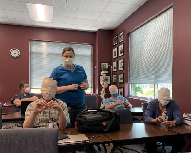 VCOM faculty sitting with wraps covering their faces