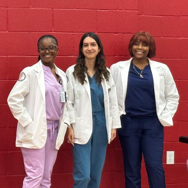 Three VCOM-Louisiana students in white coats at a Pre-SOMA event