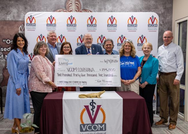 Large group holding an oversized check at VCOM-Louisiana