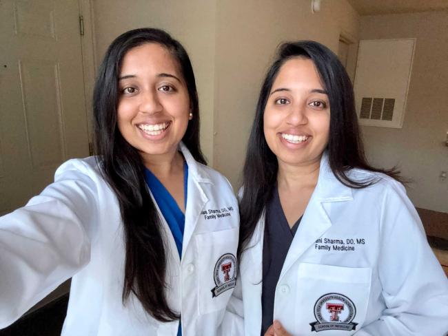 Drs. Ishani and Shivani Sharma in whitecoats smiling