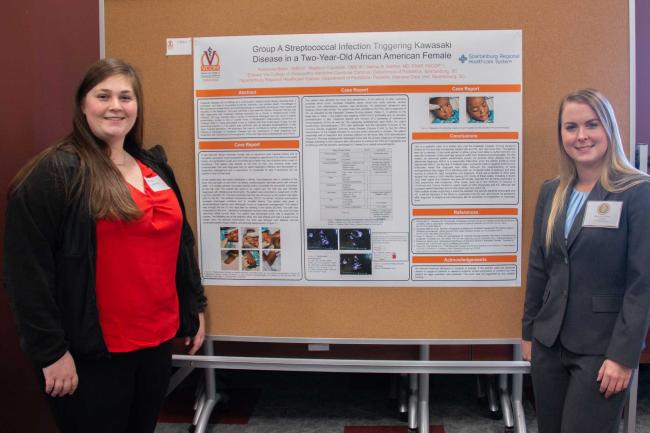 Medical student standing in front of their research day poster
