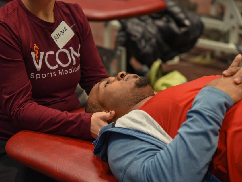 Woman demonstrating osteopathic manipulative treatment with hands on shoulders of patient lying on a table