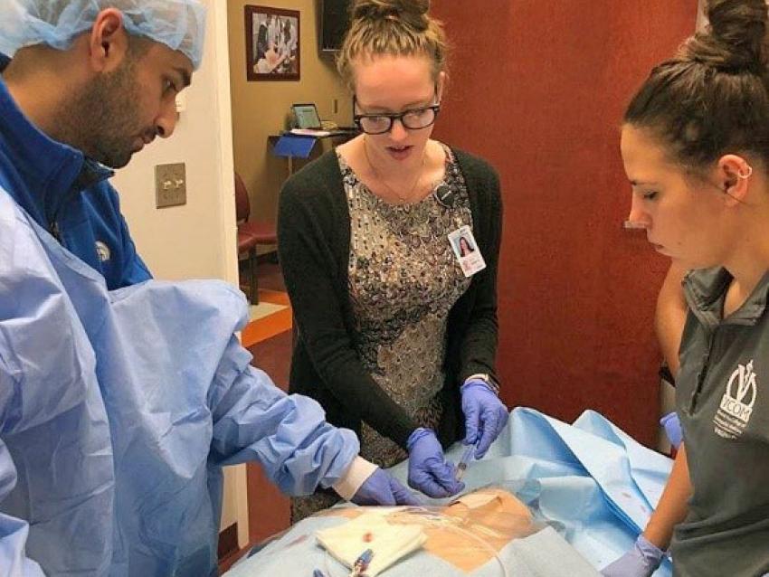 Students standing over patient