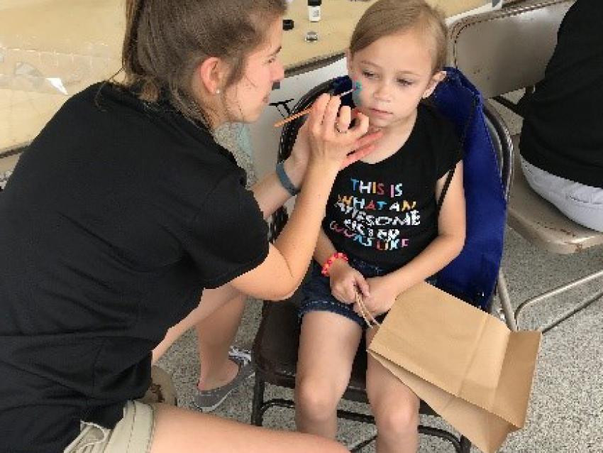 Student face painting on child