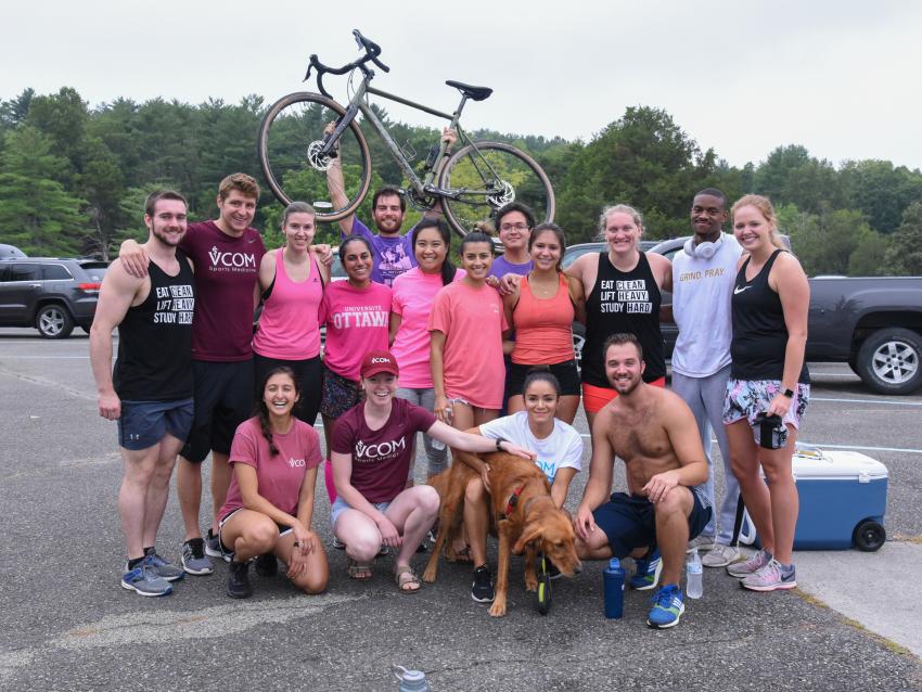 participants in VCOM's annual sports medicine adventure race hold a mountain bike overhead