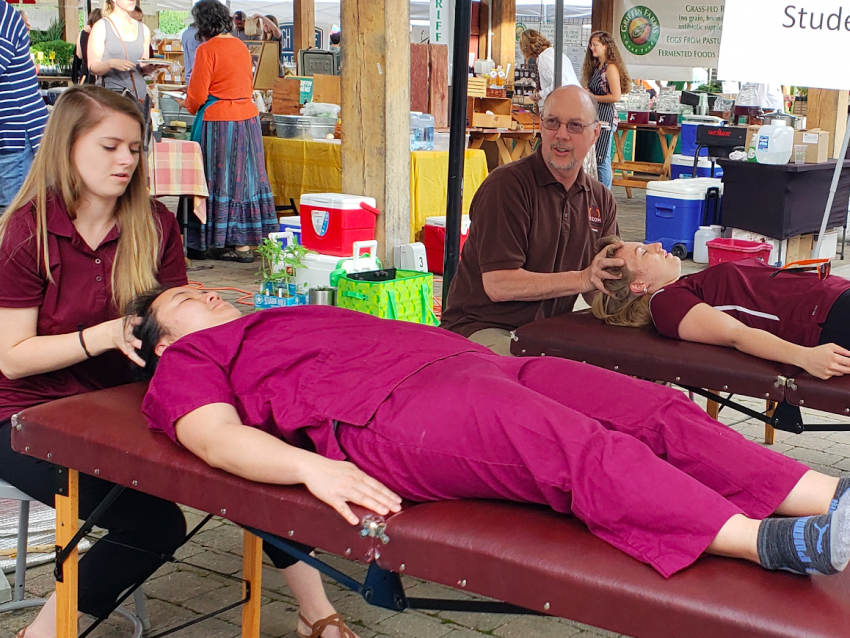 Student and faculty administering OMM at farmer's market