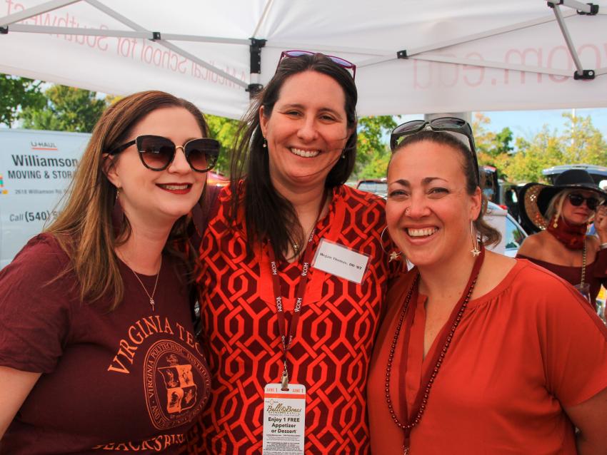 Three alumni pose for a picture at a tailgating party.
