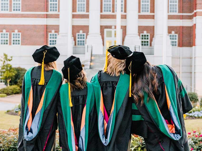 Graduates standing in front of Auburn campus