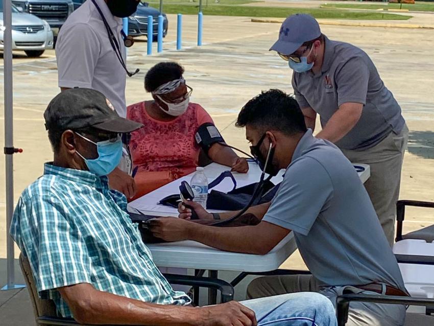 Medical student reading blood pressure of health fair attendee