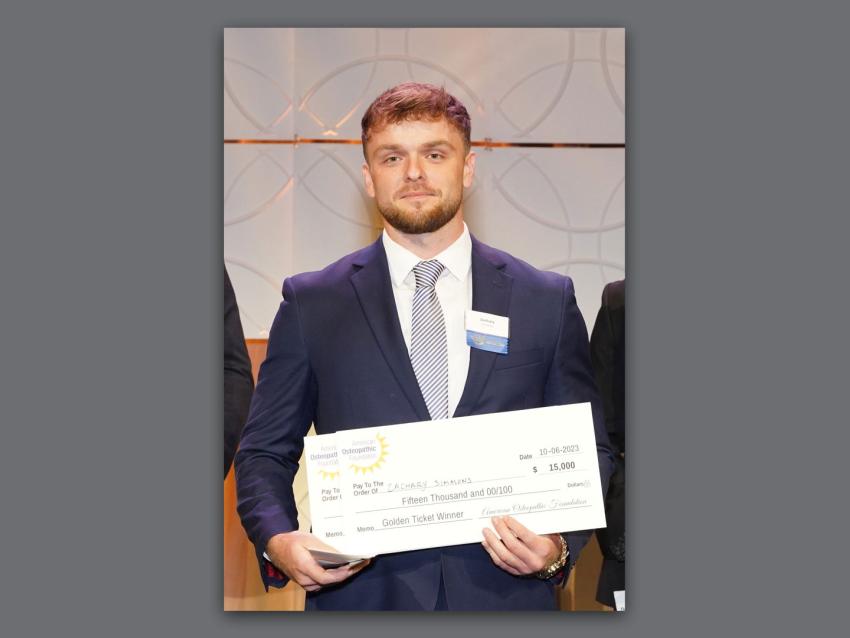 Zach Simmons holding an award check