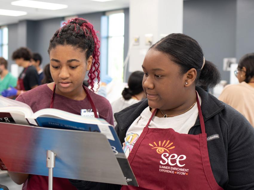 Two high school students reading a book at Carolinas Summer Enrichment Experience