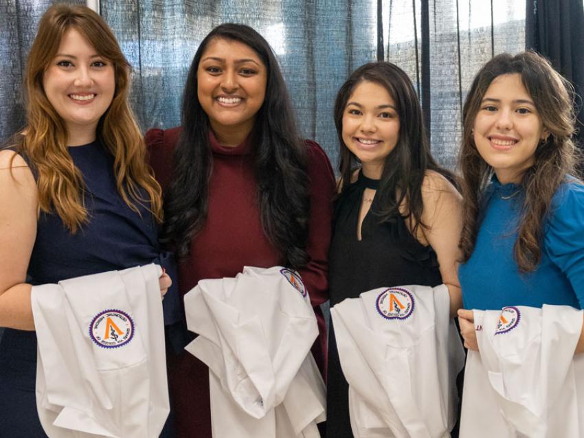 Students posing with white coats on their arms