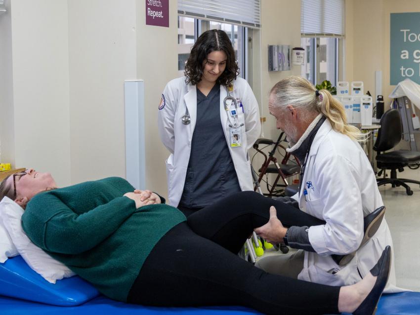 Faculty teaching student OMM techniques with patient