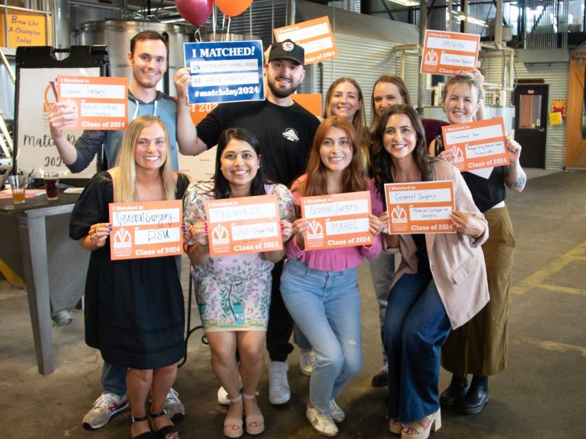 Carolinas students posing with match day posters