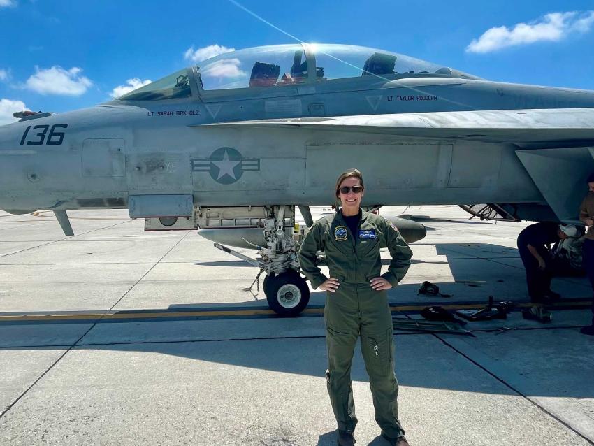 Taylor Rudolph standing in front of a fighter jet with her name under the cockpit