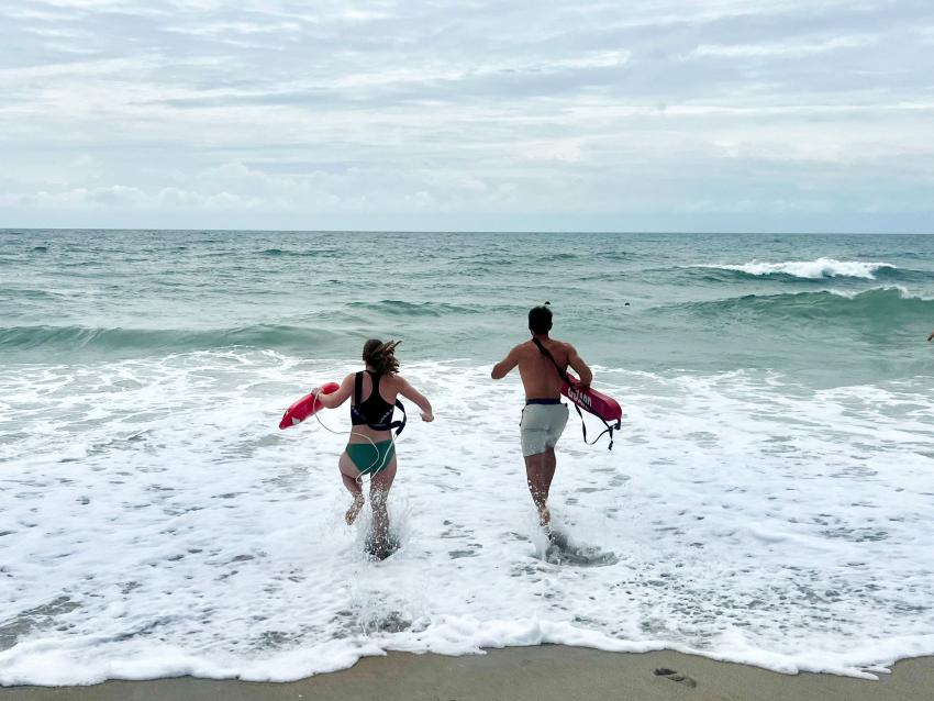 Two lifeguards running out into the ocean to a practice rescue