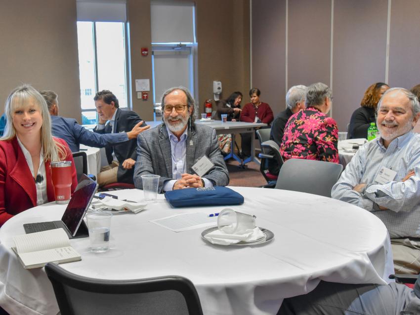VCOM research retreat attendess sitting around a table smiling