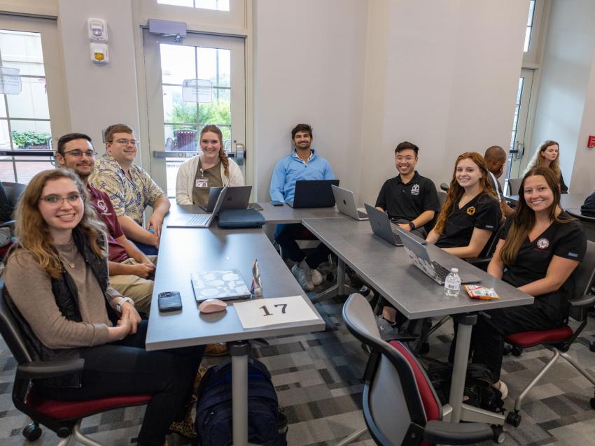 VCOM - Louisiana and ULM students sitting around a table smiling