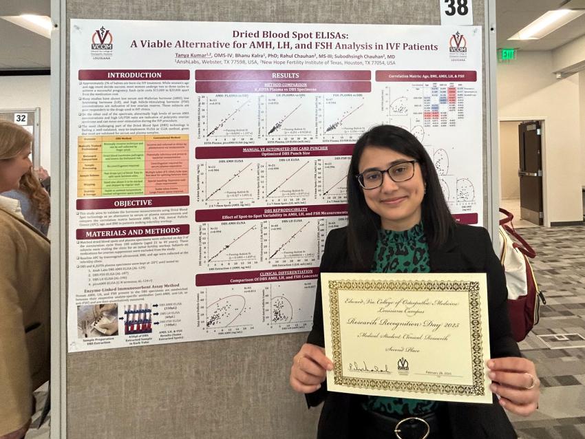Tanya Kumar holding her award standing in front of her research poster