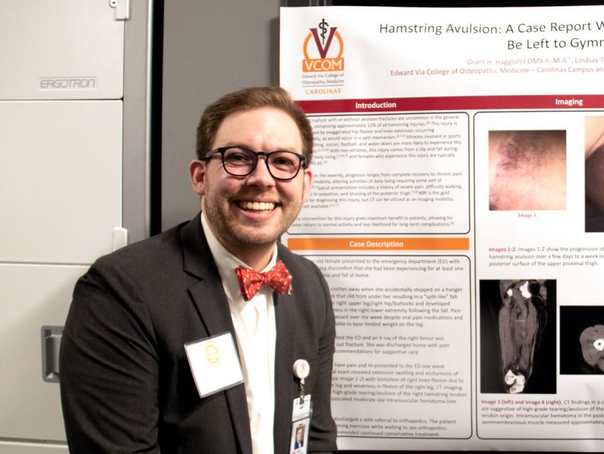 VCOM-Carolinas student smiling in front of his research day poster