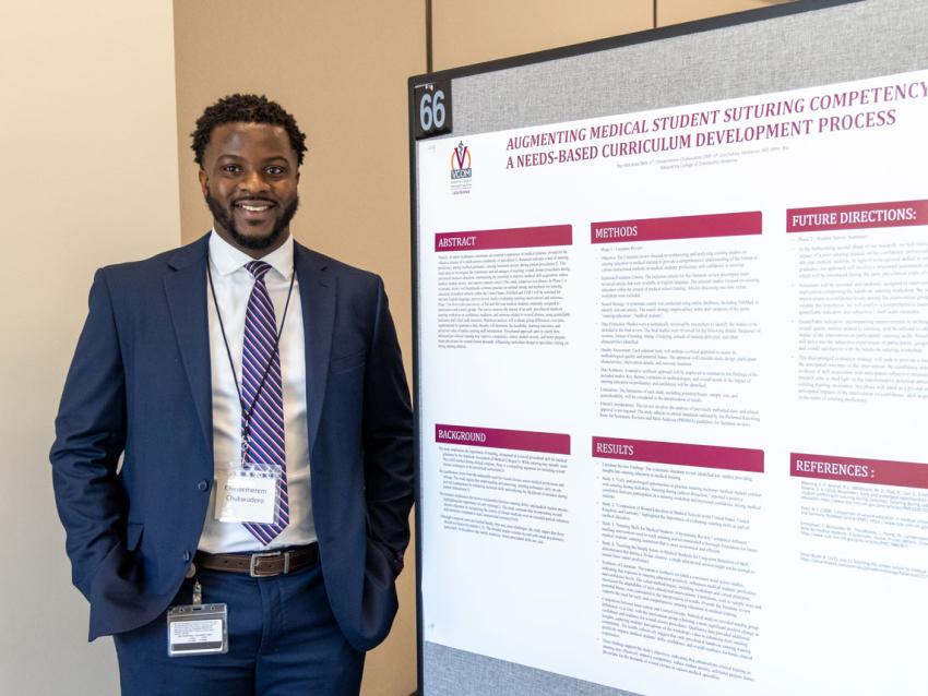VCOM-Louisiana student smiling in front of his research day poster