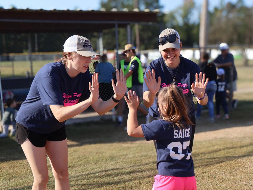 VCOM-Louisiana students high-fiving a child at an outreach event