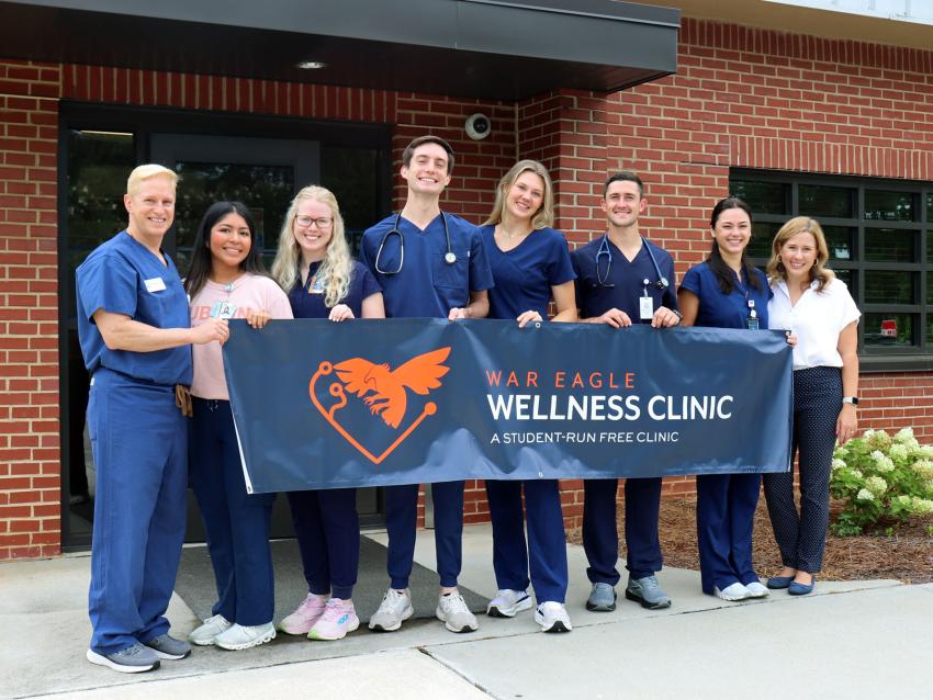 VCOM-Auburn students and staff holding a banner for the War Eagle Wellness Clinic