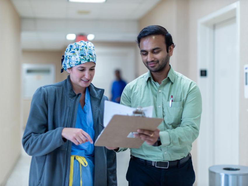 VCOM resident walking down a hallway with another physician talking while looking at a clipboard