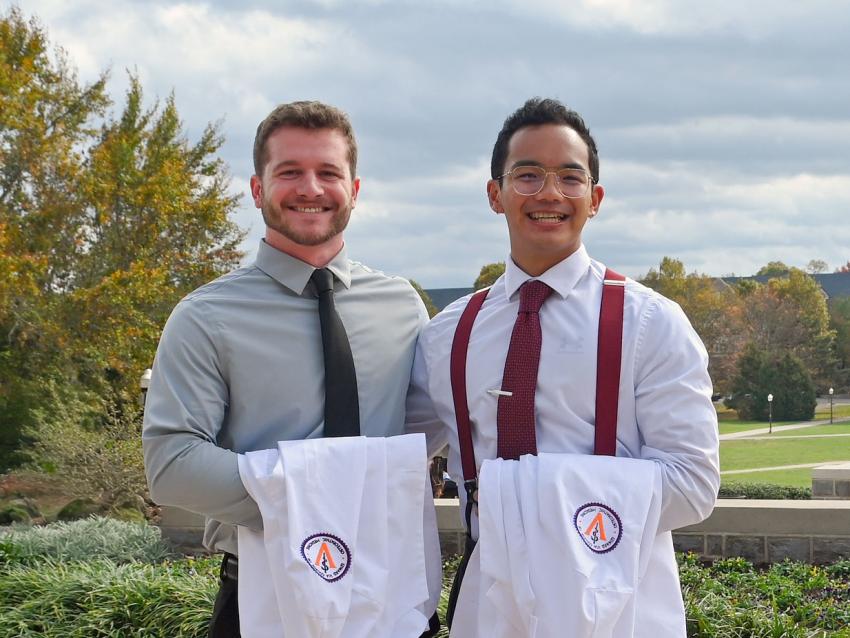 Tow VCOM-Virginia students smiling holding white coats
