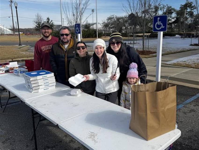 VCOM-Louisiana students standing in front of a portable table smiling