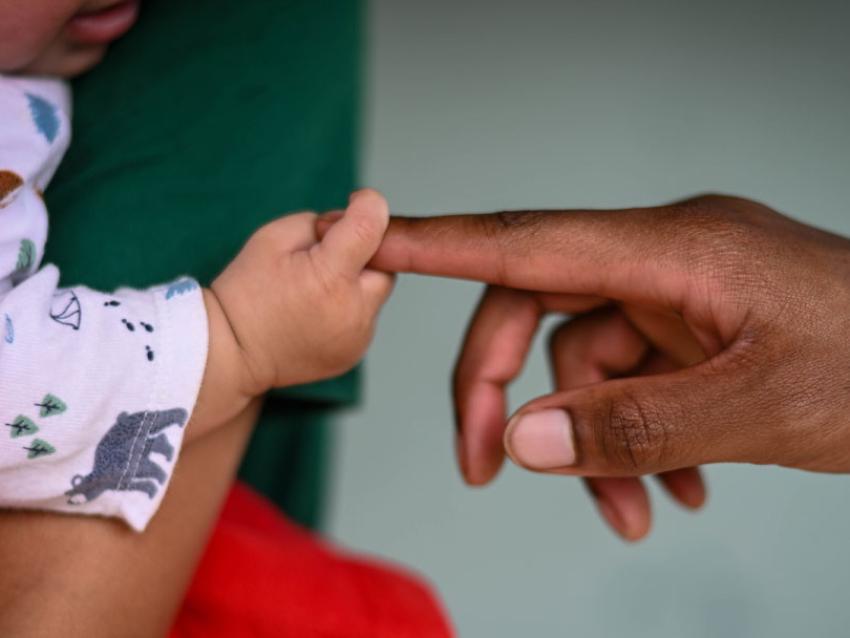 Baby's hand grasping an adult's finger