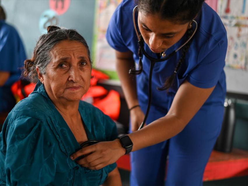 VCOM student holding a stethoscope to a woman's chest in Honduras