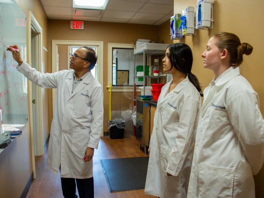 Bidyut Mohanty drawing on a white board in front of two student doctors