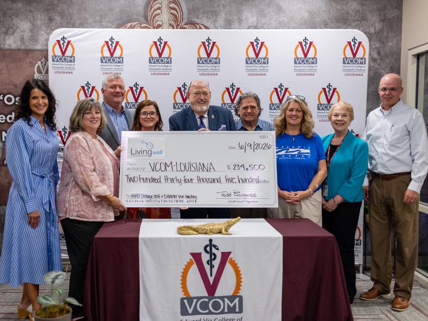 Large group holding an oversized check at VCOM-Louisiana