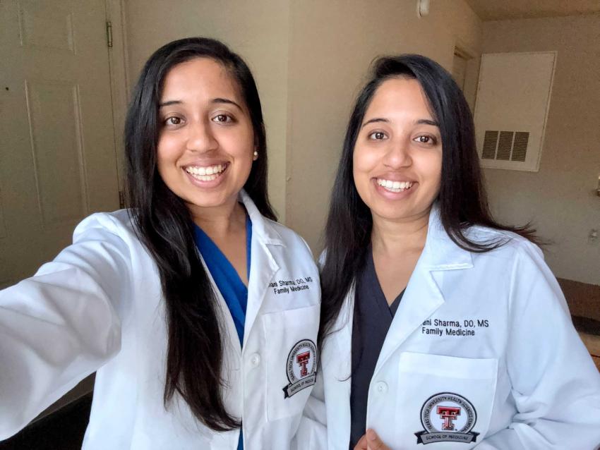Drs. Ishani and Shivani Sharma in whitecoats smiling