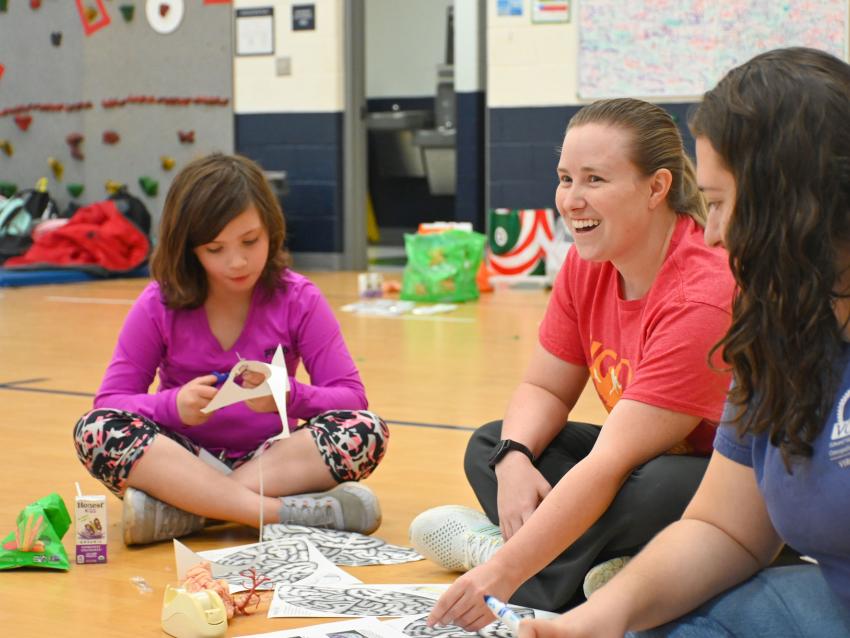 Medical student sitting on the floor with child working on a paper brain project