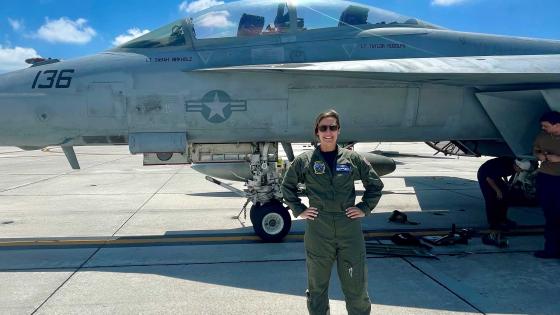 Taylor Rudolph standing in front of a fighter jet with her name under the cockpit