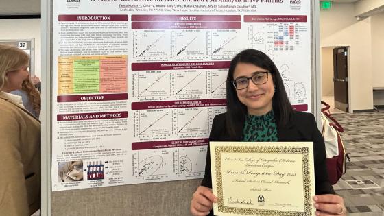 Tanya Kumar holding her award standing in front of her research poster