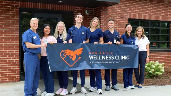 VCOM-Auburn students and staff holding a banner for the War Eagle Wellness Clinic