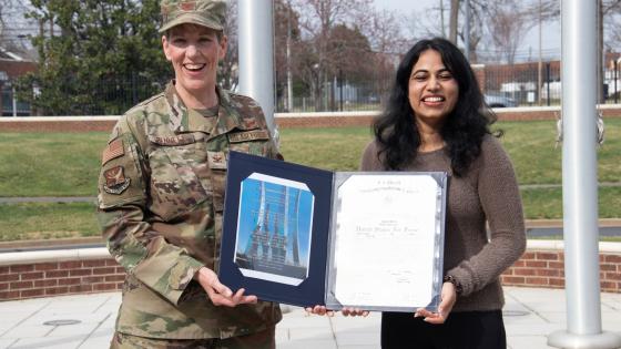 VCOM-Carolinas student holding her commissioning certificate with an Army member
