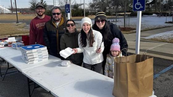VCOM-Louisiana students standing in front of a portable table smiling