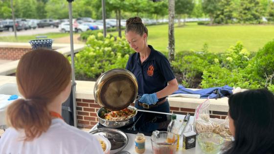 Dr. Annie Kirby cooking food outside for students.