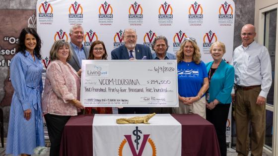 Large group holding an oversized check at VCOM-Louisiana
