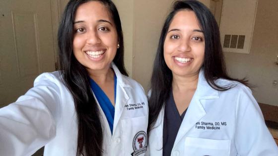 Drs. Ishani and Shivani Sharma in whitecoats smiling