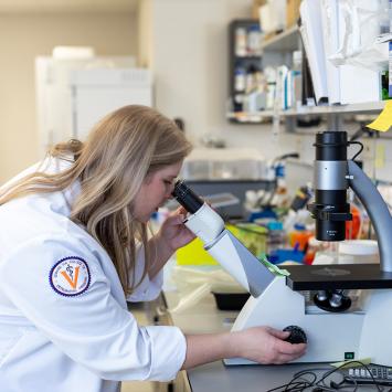 Jenna Dittmar looks into a microsope